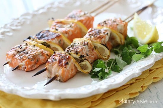 Grilled salmon kabobs garnished with herbs and lemon. 