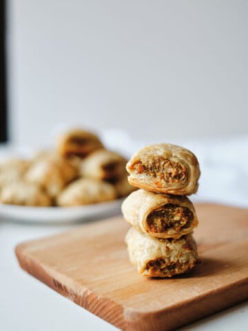 sausage rolls stacked on cutting board