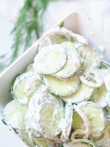 creamy cucumber salad in white serving dish