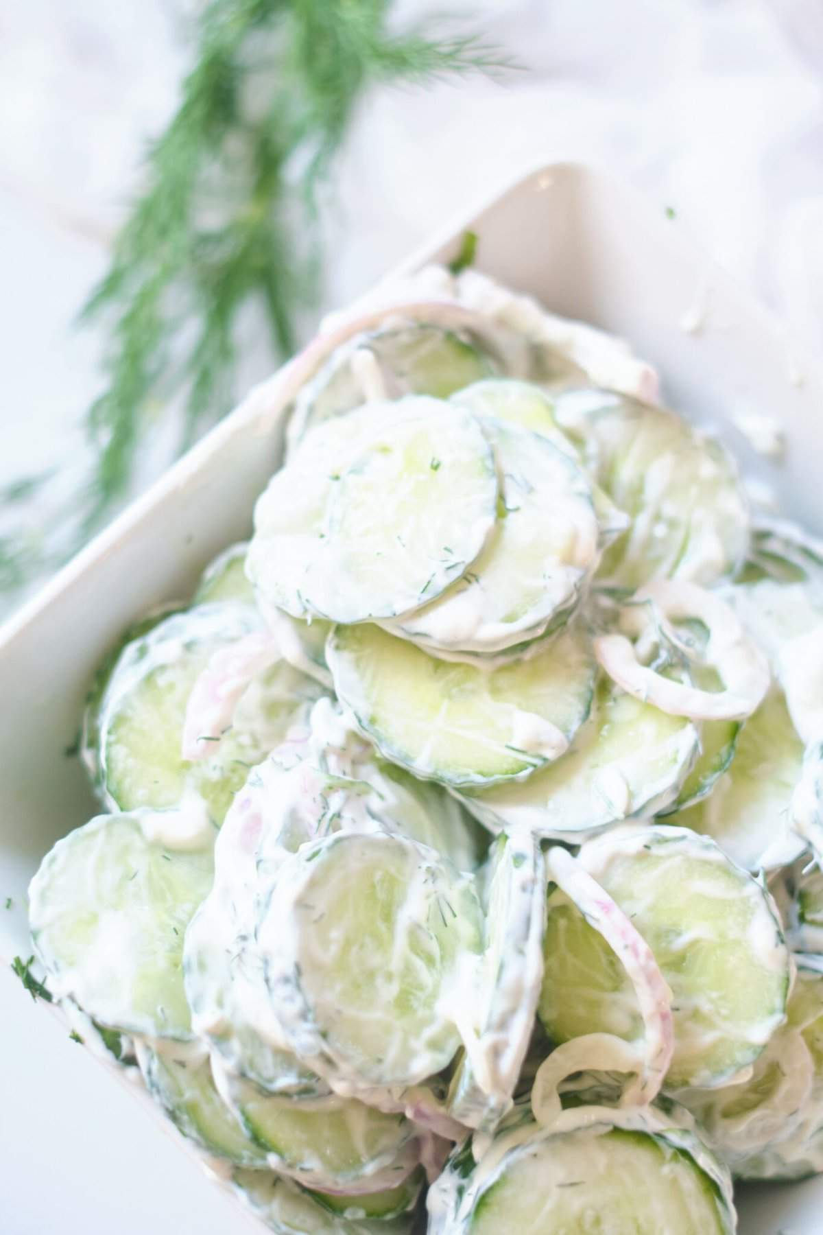 creamy cucumber salad in white serving dish