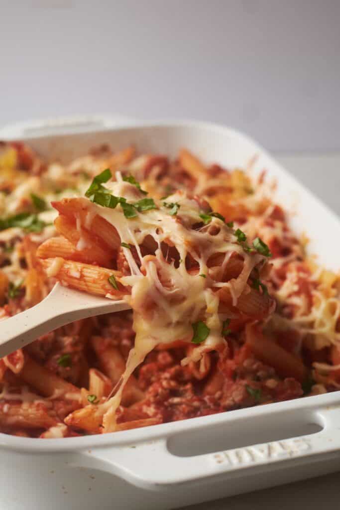 Finished cheesy penne pasta with ground turkey in a white serving dish.