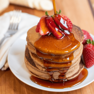 ww friendly banana and strawberry oat pancakes topped with strawberries and syrup.