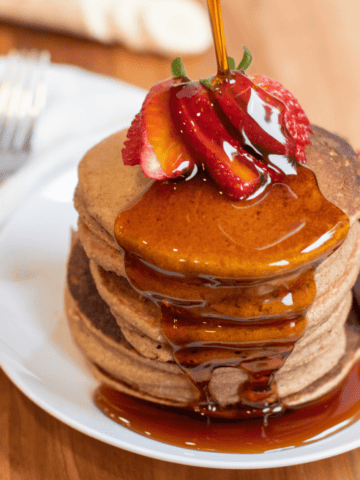 ww friendly banana and strawberry oat pancakes topped with strawberries and syrup.