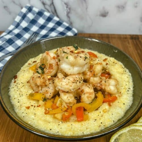 Bowl of shrimp and grits with lemon and napkin