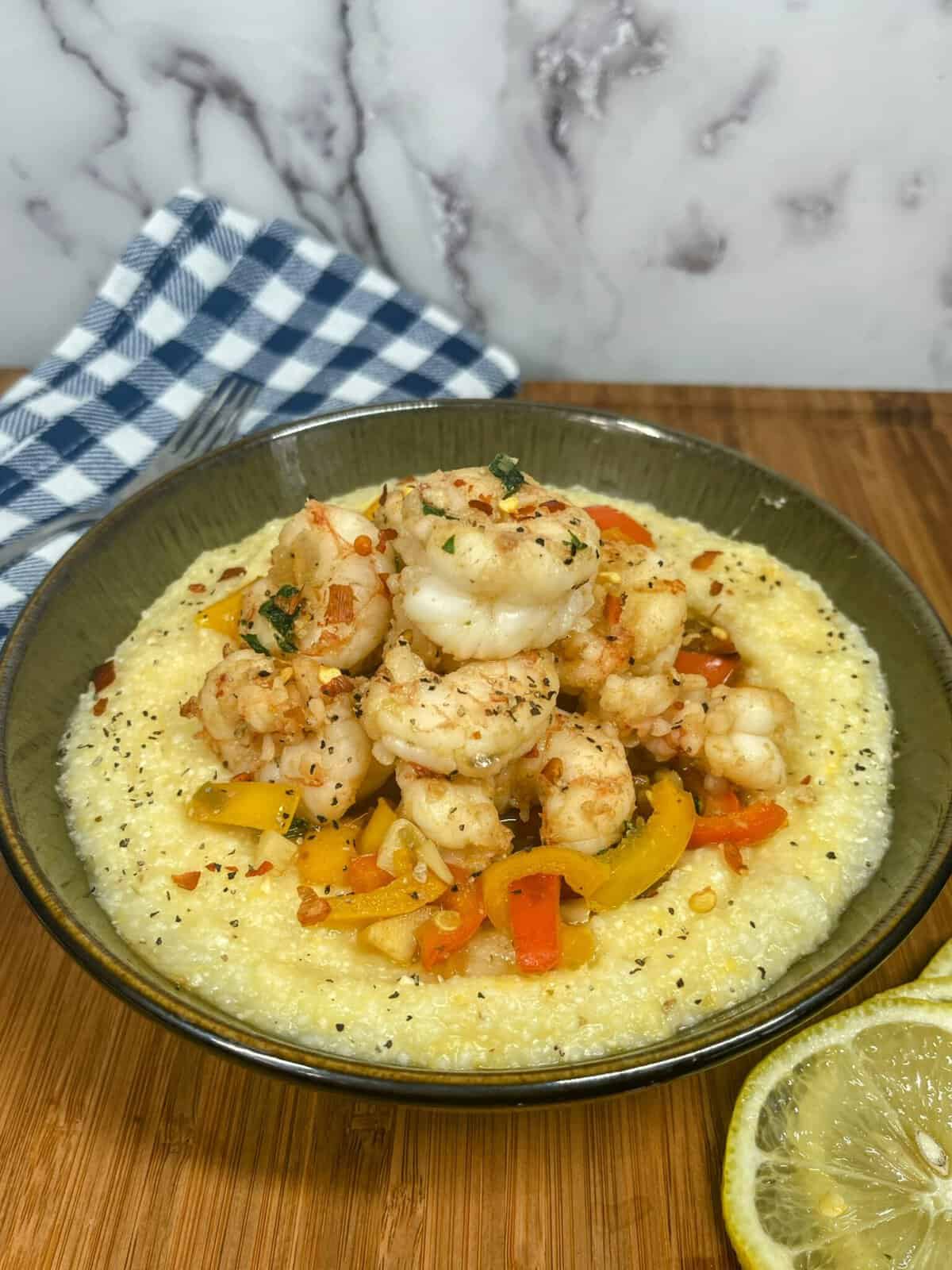 Bowl of shrimp and grits with lemon and napkin
