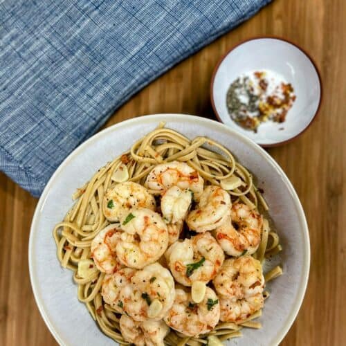 shrimp scampi in pasta bowl with small bowl of spices