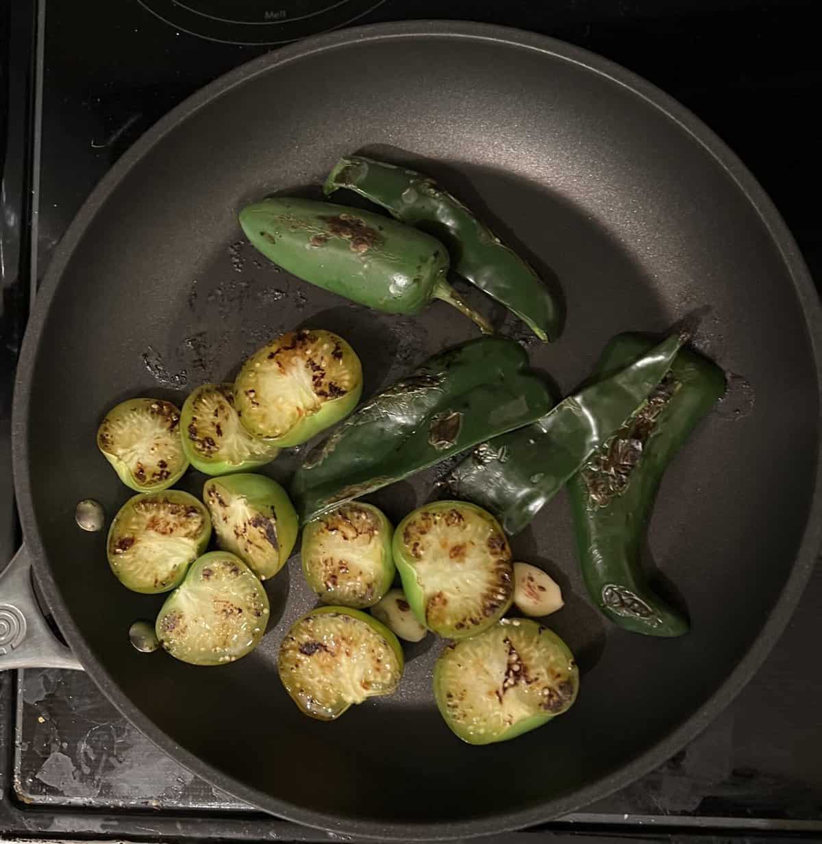 Poblanos, tomatillos, and garlic roasting in pan