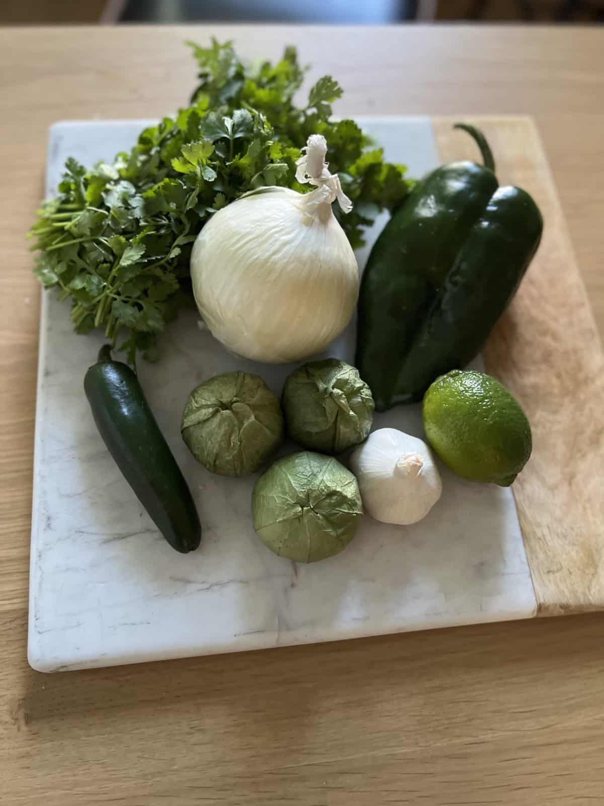 Fresh ingredients for roasted poblano salsa on a cutting board.