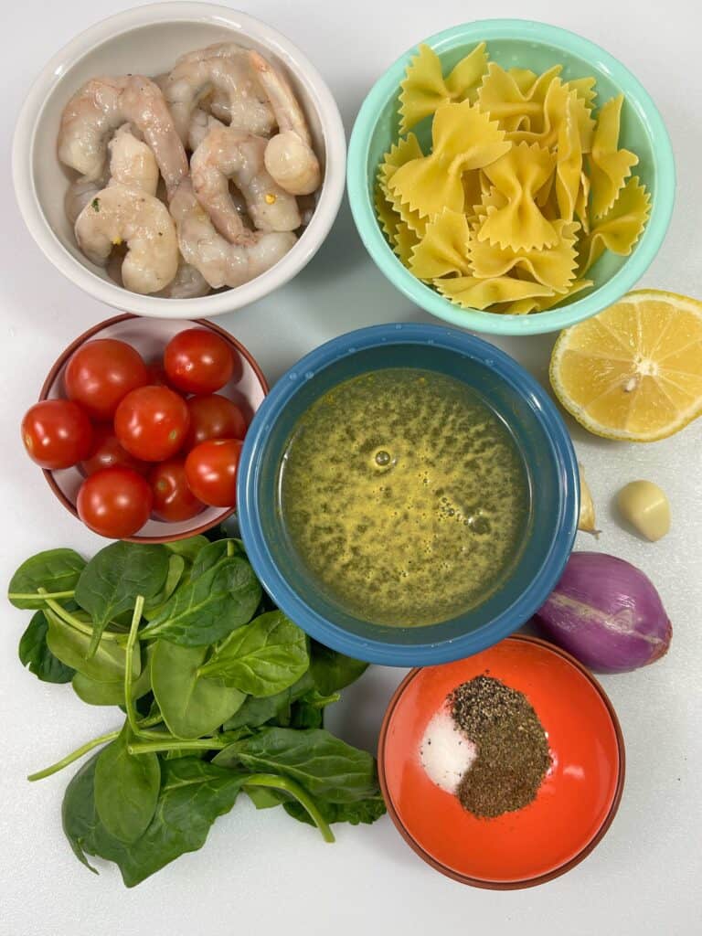 Shrimp pasta ingredients of shrimp, pasta noodles, cherry tomatoes, lemon, spinach 