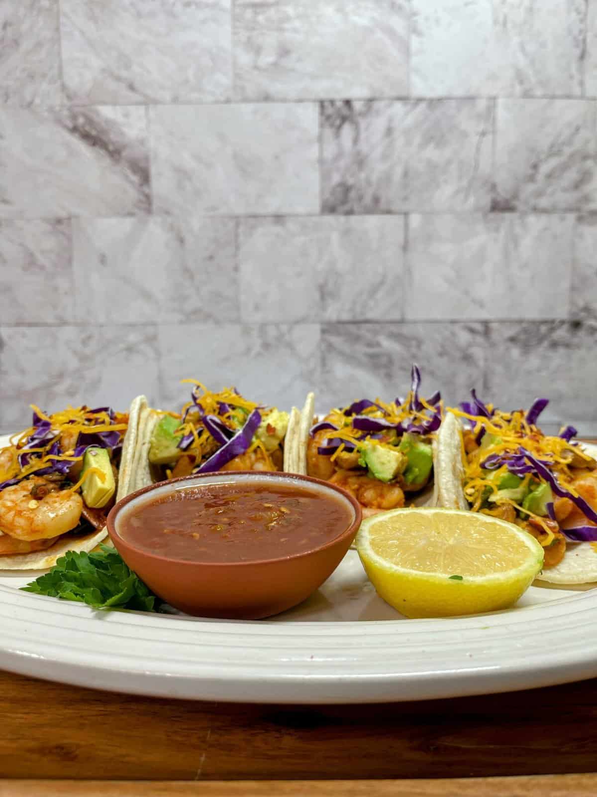 four chipotle shrimp tacos with salsa and a lemon