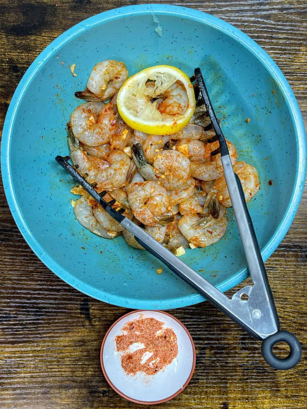 bowl of raw shrimp, garlic, seasoning, and lemon tossed