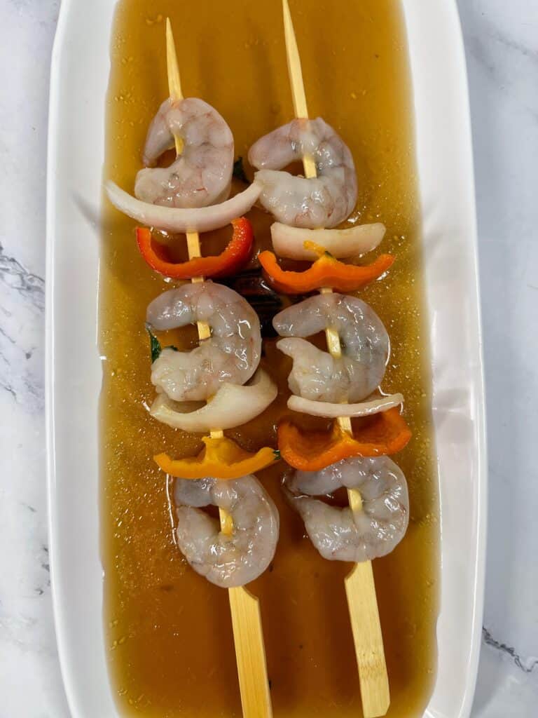 uncooked shrimp skewers in marinade