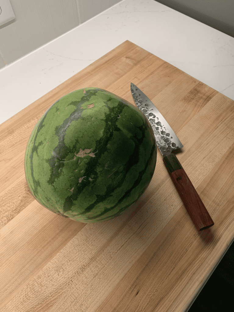 watermelon on cutting board with chef's knife