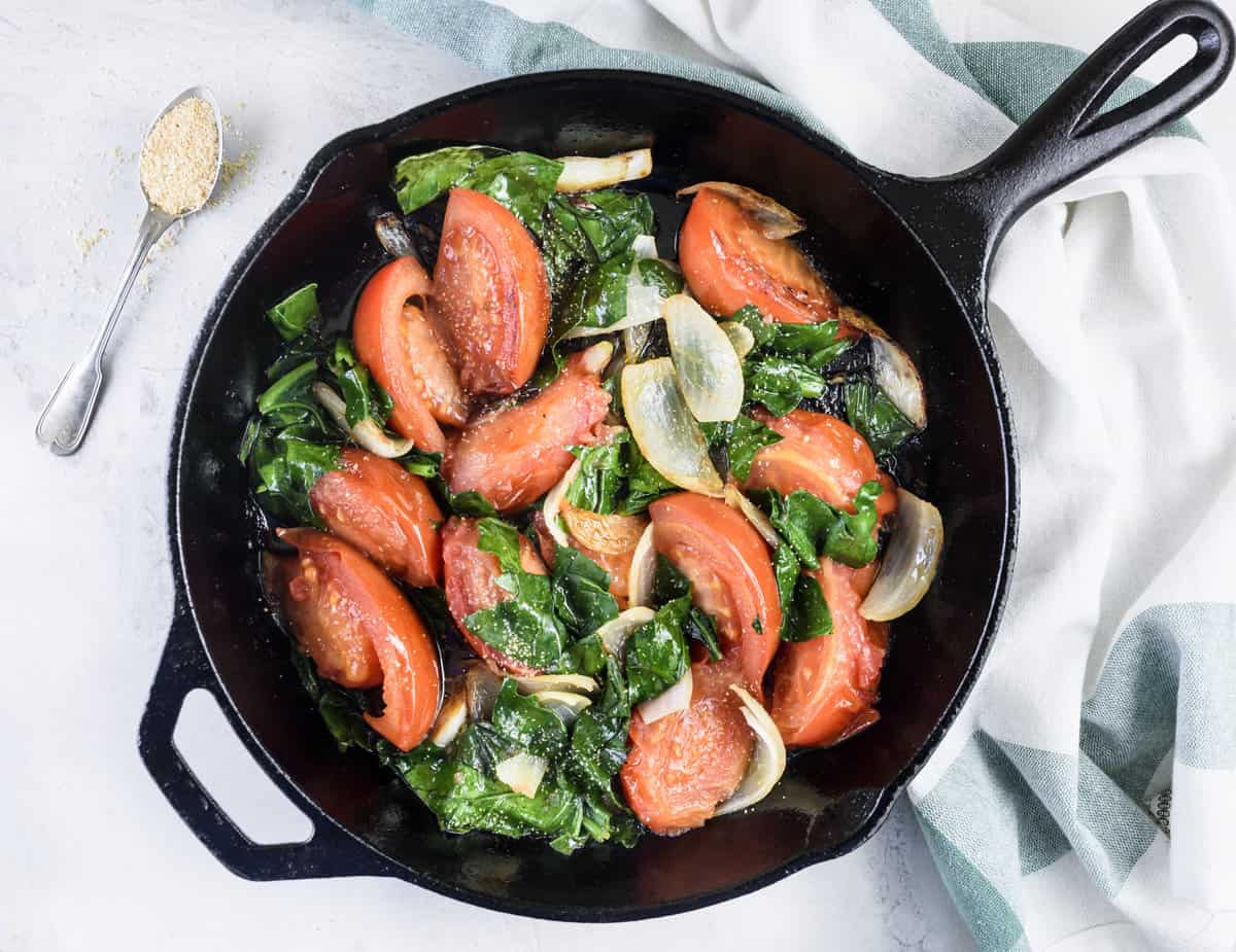 tomatoes, onions and spinach in black frying pan