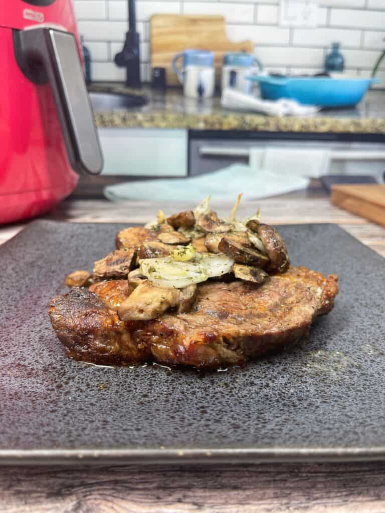 cooked ribeye up close with sautéed mushrooms