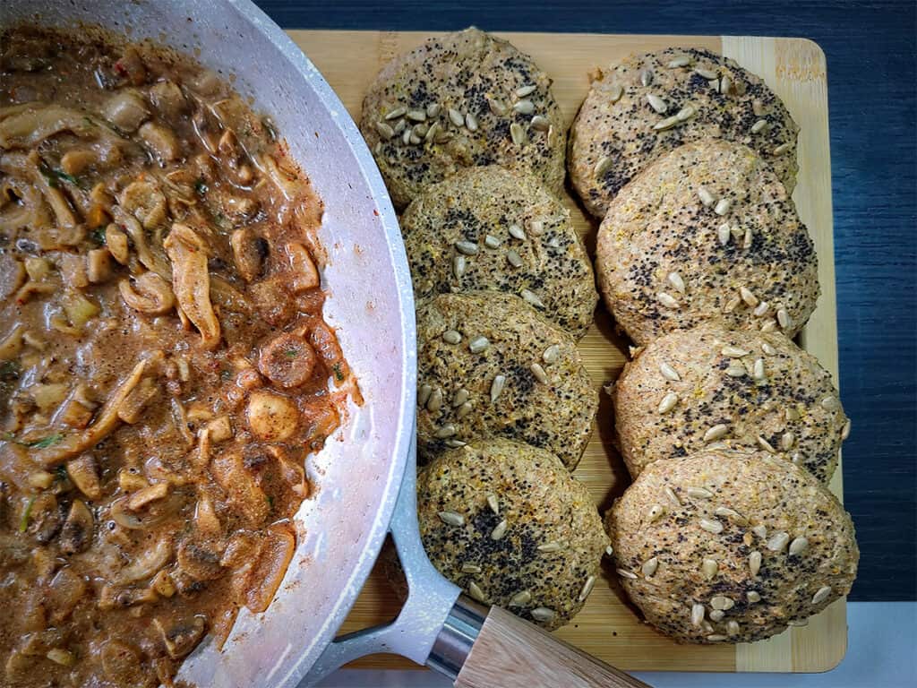 Vegan gravy in white bowl sitting next to plate of vegan biscuits