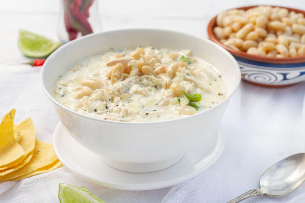 white chicken chili in white bowl with limes
