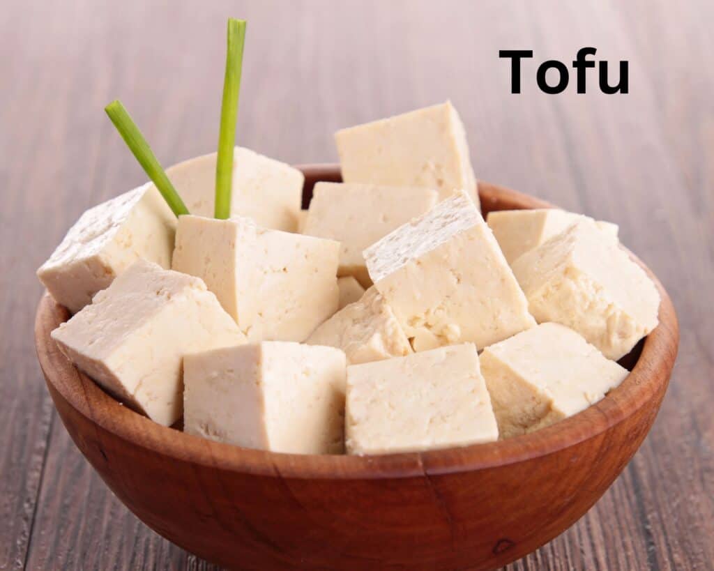 Chopped tofu sitting in wooden bowl