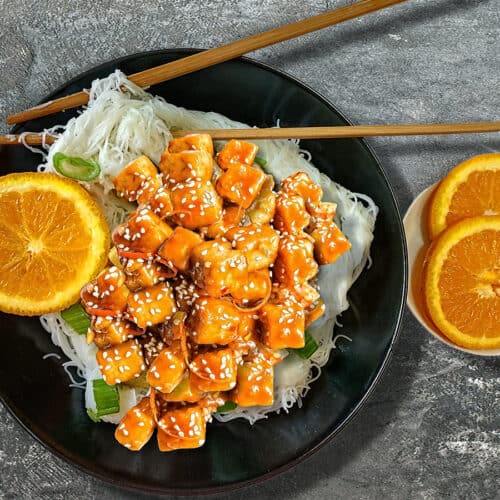 orange tofu in black bowl