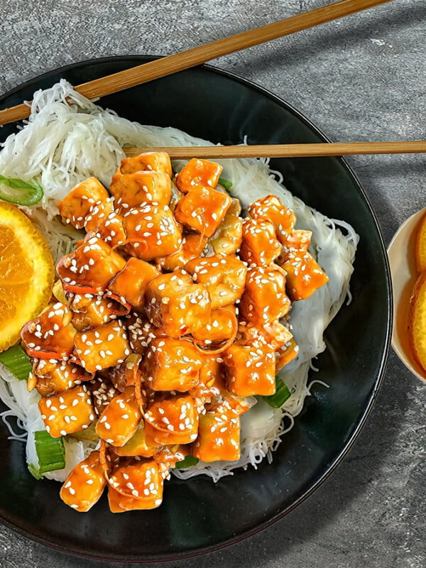 orange tofu in black bowl