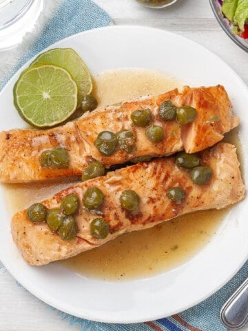 two pieces of salmon piccata on white plate