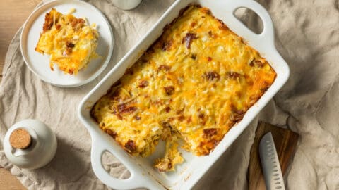 Breakfast casserole in white baking sheet with one piece cut out on white plate