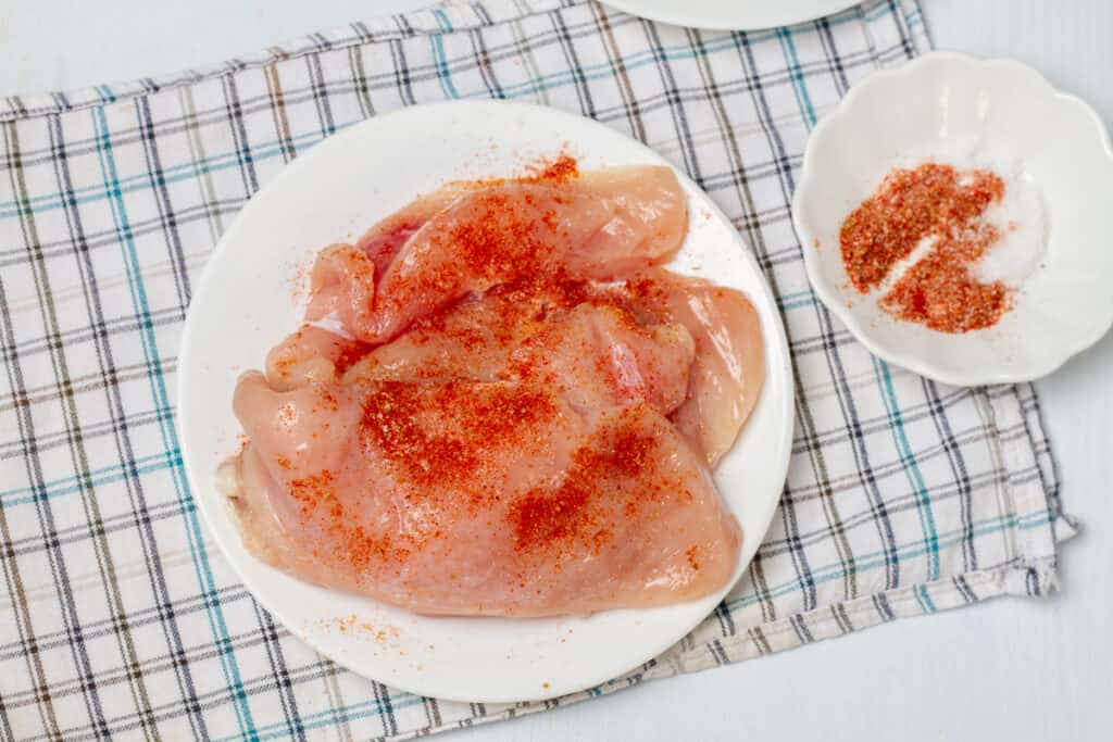 Raw chicken breasts with taco seasoning on a plate. 