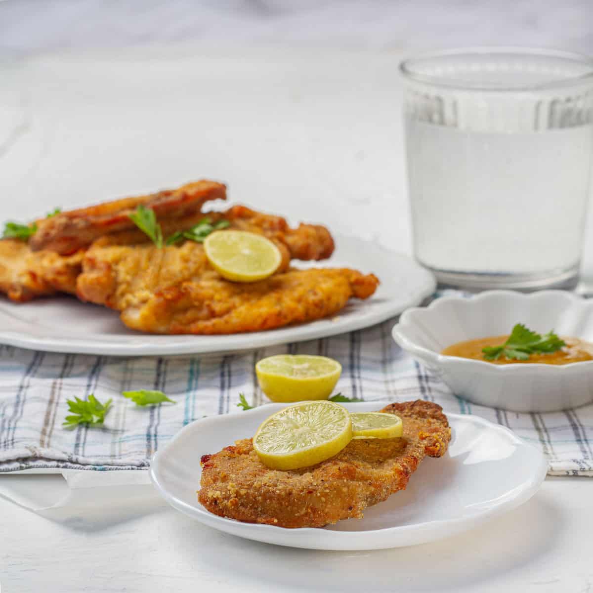 Crispy air fryer chicken cutlets garnished with fresh herbs and lemon slices.