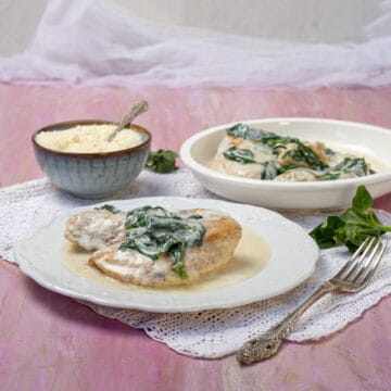 Creamy chicken Florentine topped with sauteed spinach on a plate.