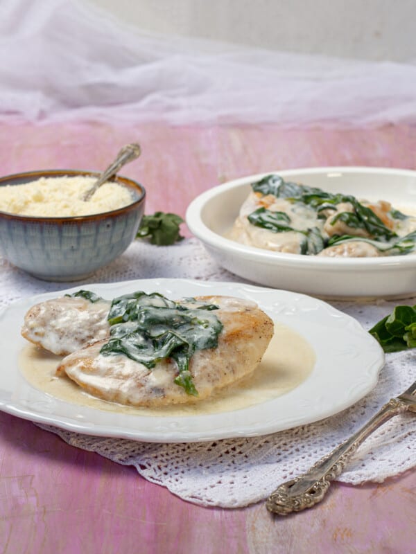 Creamy chicken Florentine topped with sauteed spinach on a plate.