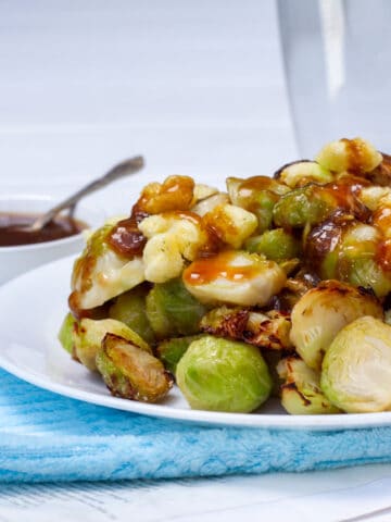 Crispy Brussel sprouts drizzled in a soy ginger glaze, on a plate.