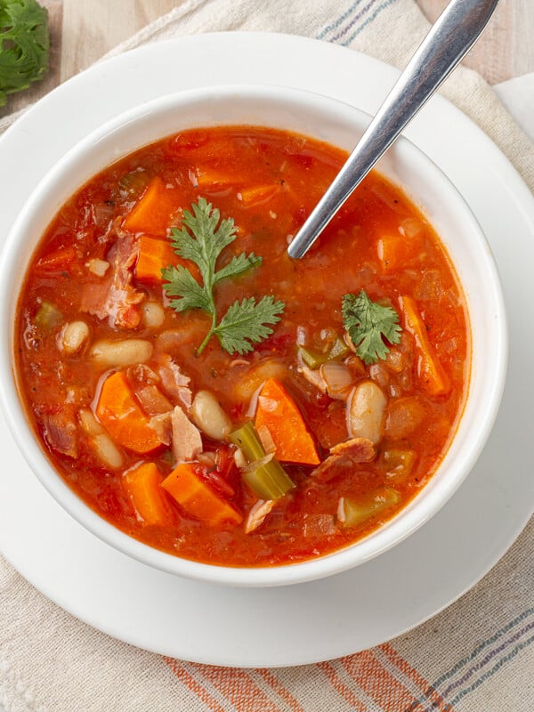 Ham and bean soup in a bowl with spoon.