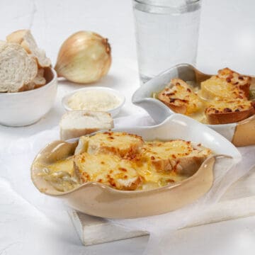 French onion soup in two bowls topped with bread and melted cheese.