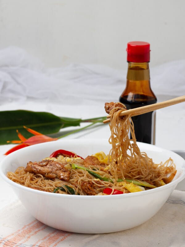 A bowl of pad woon sen, or stir-fried glass noodles. The Thai dish is comprised of thin stir-fried noodles with colorful veggies in a brown sauce.