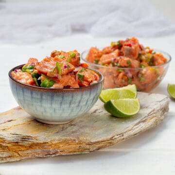 Salmon Ceviche in two bowls with lime wedges.