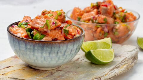 Salmon Ceviche in two bowls with lime wedges.