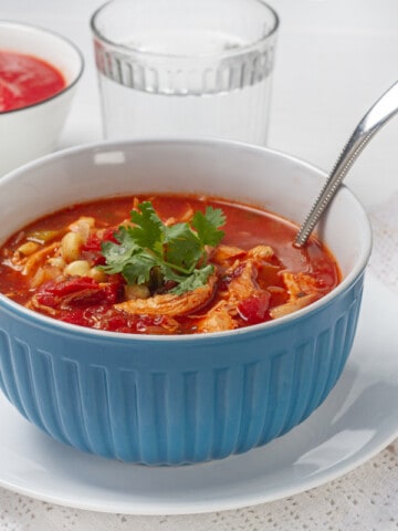 Tomato-based Southwest chicken soup in a bowl with a spoon.