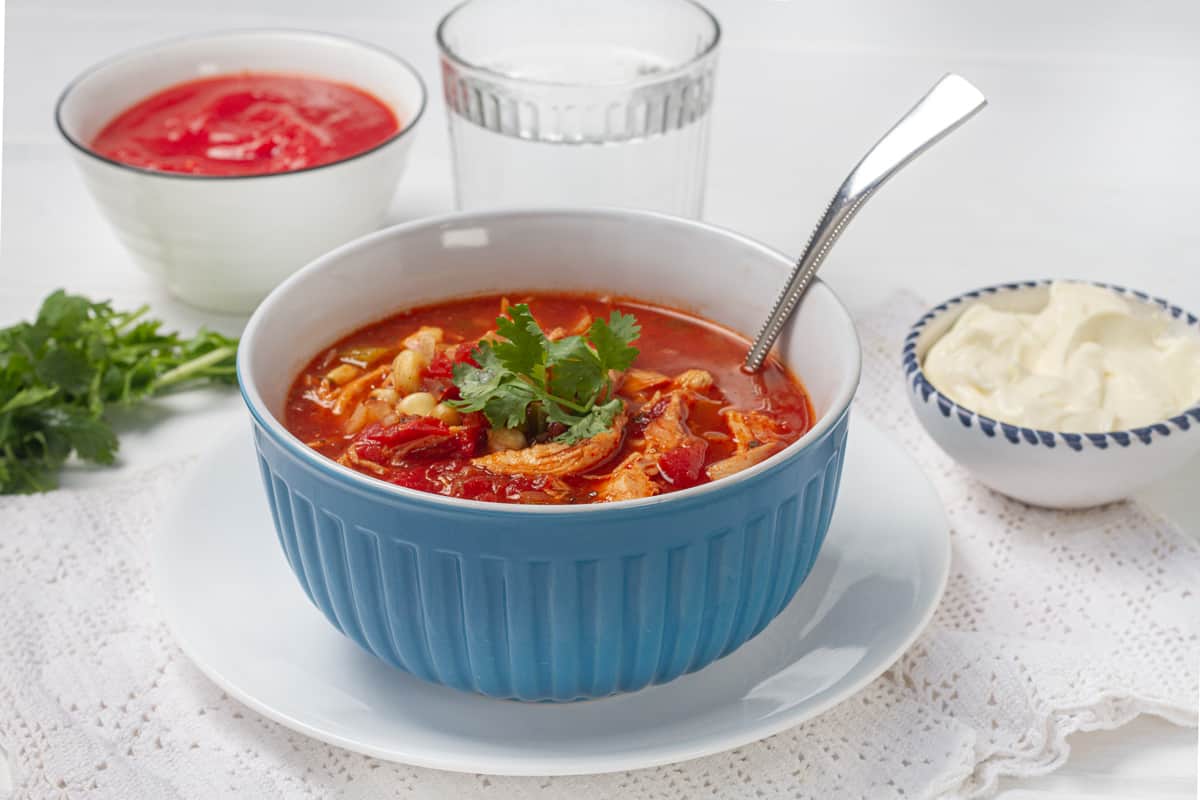 Tomato-based Southwest chicken soup in a bowl with a spoon.