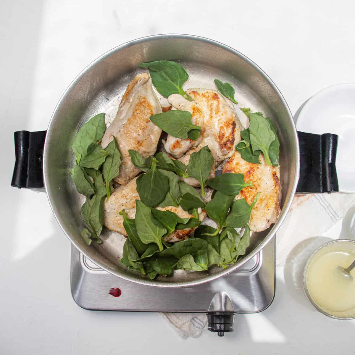 Chicken and spinach cooking in a hot pan. 