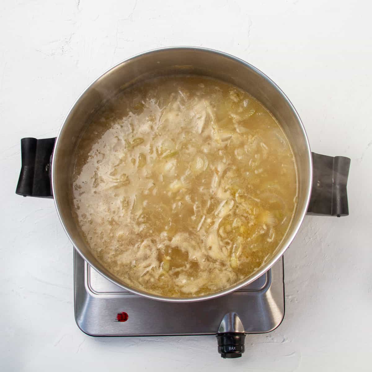Caramelized onions in broth, cooking in a hot pan.