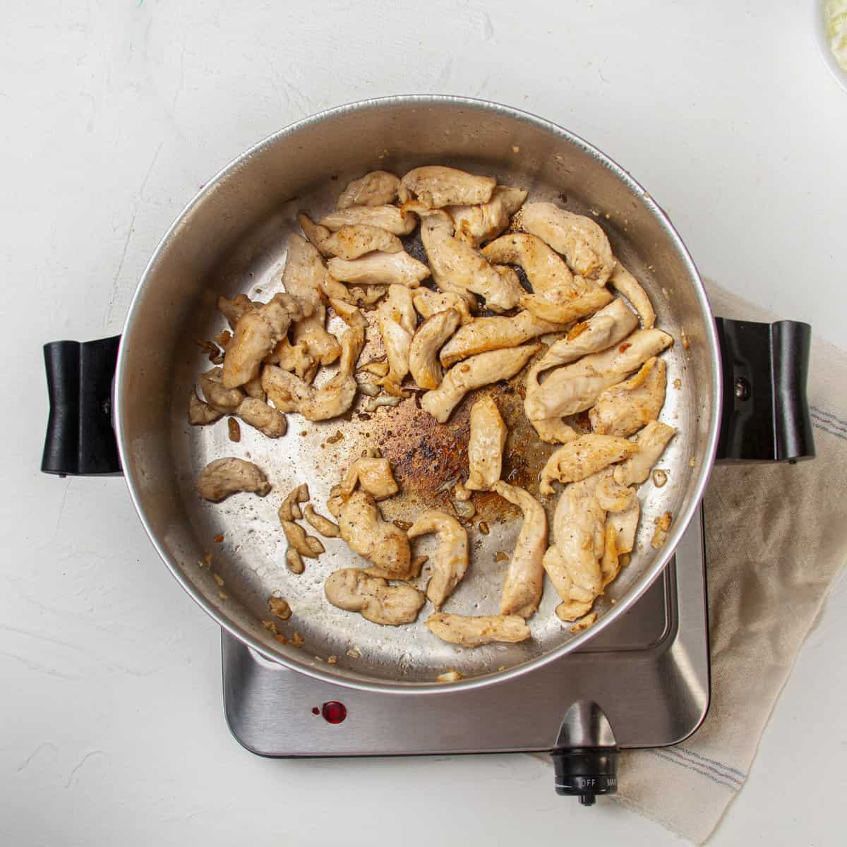 Chicken stir-frying in a pan. 