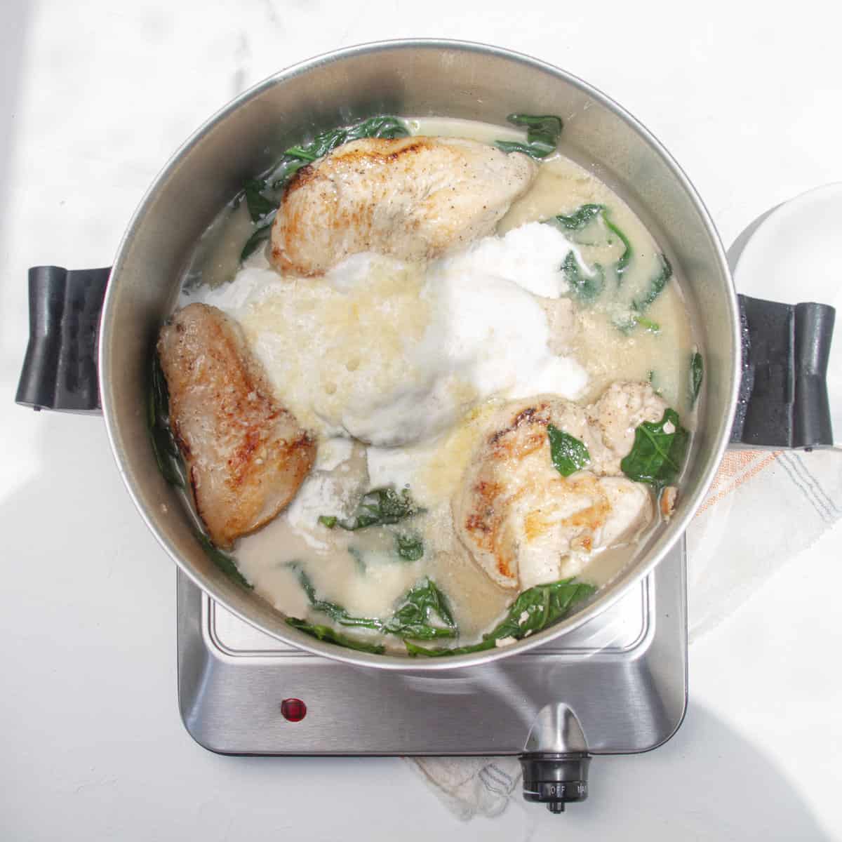 Chicken and spinach cooking in a cream sauce. 