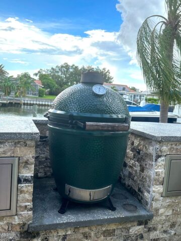 big green egg sitting on patio by water