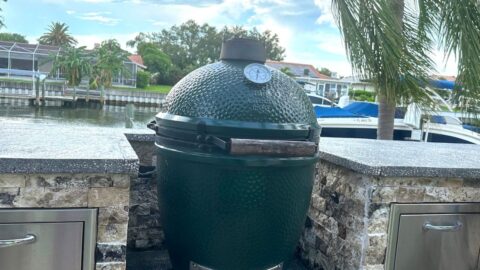 big green egg sitting on patio by water