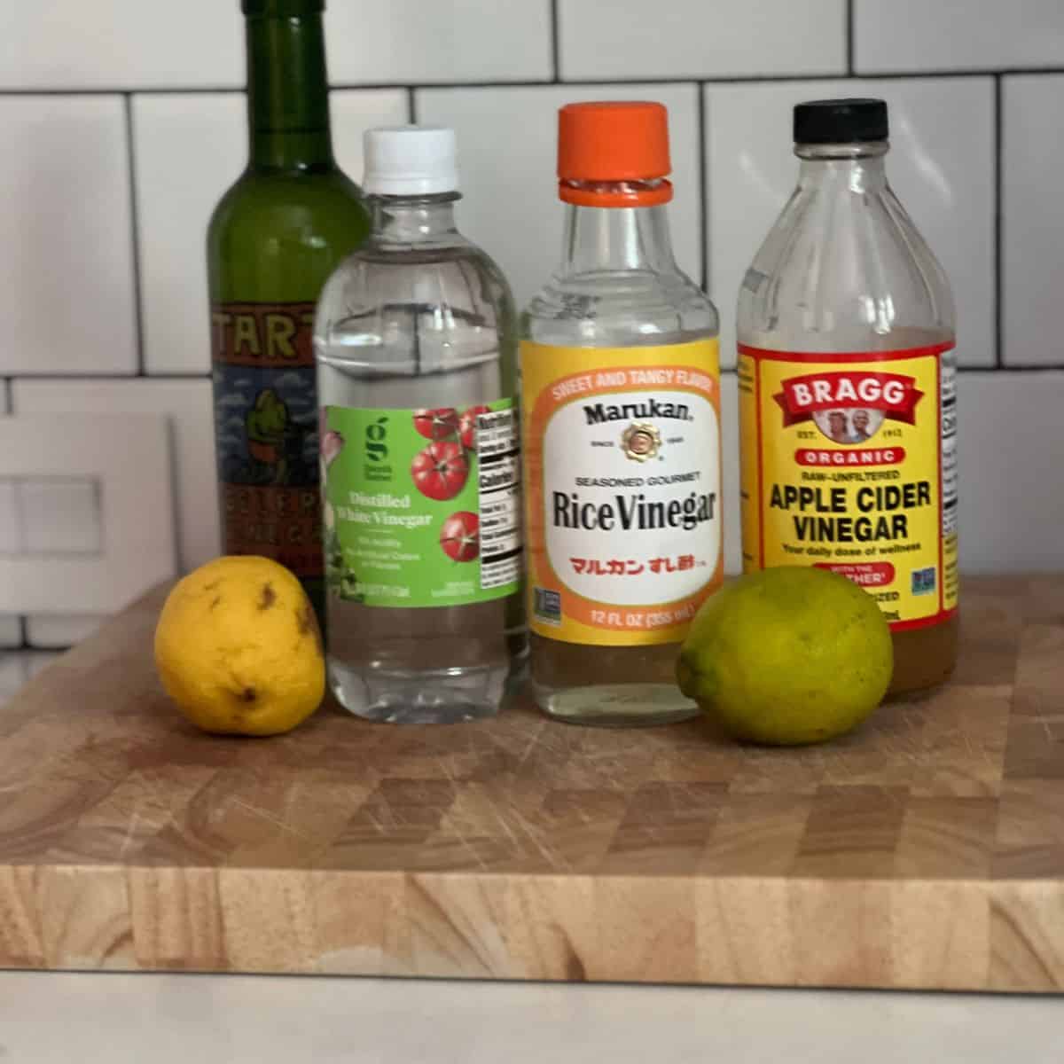 a collection of vinegar bottles on wooden cutting board