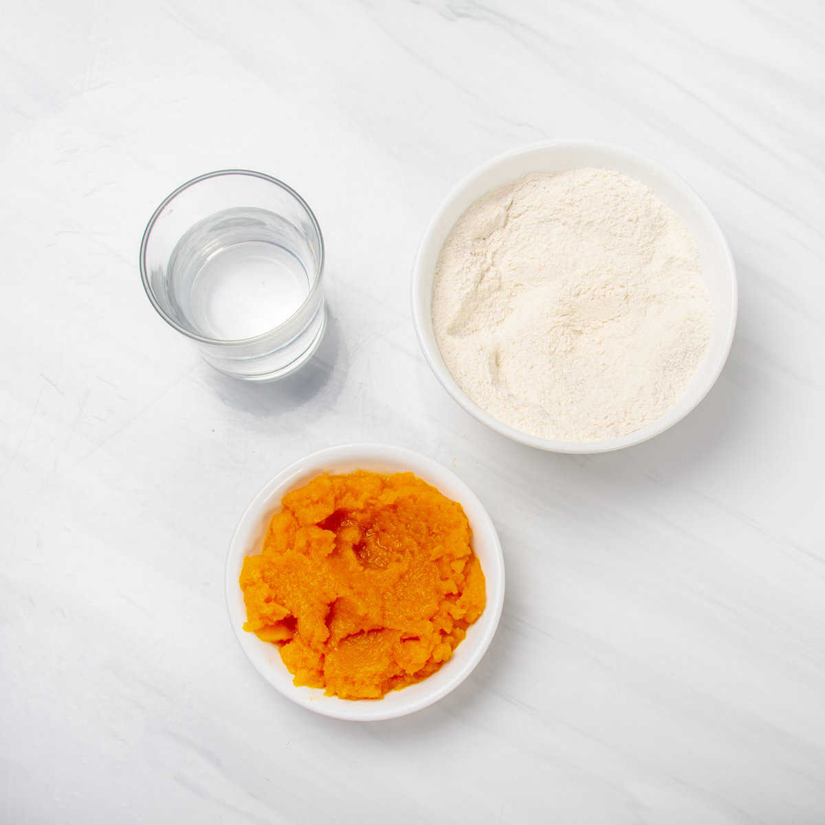 Pumpkin cake mix, pumpkin puree, and water in separate dishes. 