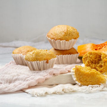 Pumpkin muffins in wrappers on a plate.