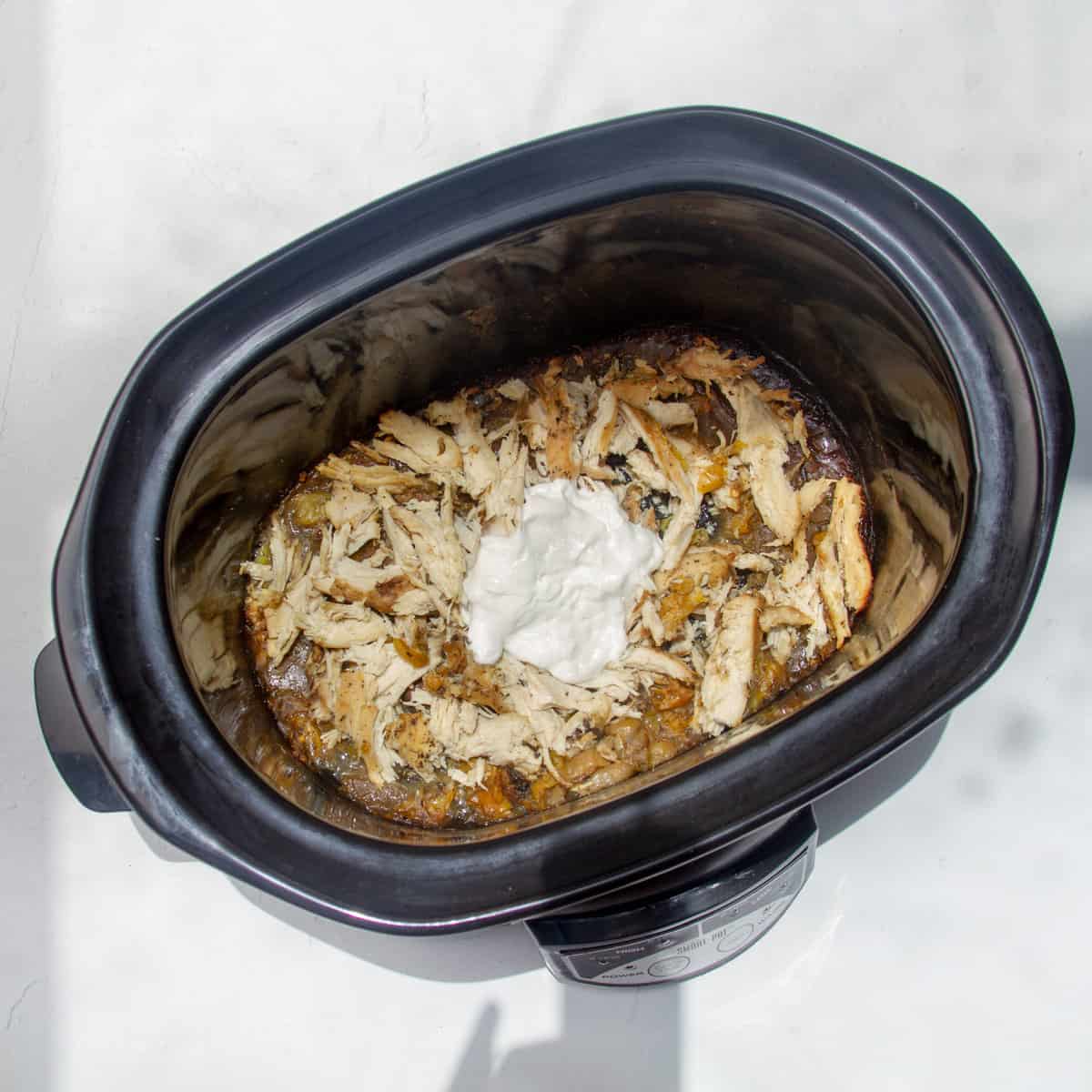 Cooked and shredded Mississippi chicken in a slow cooker.