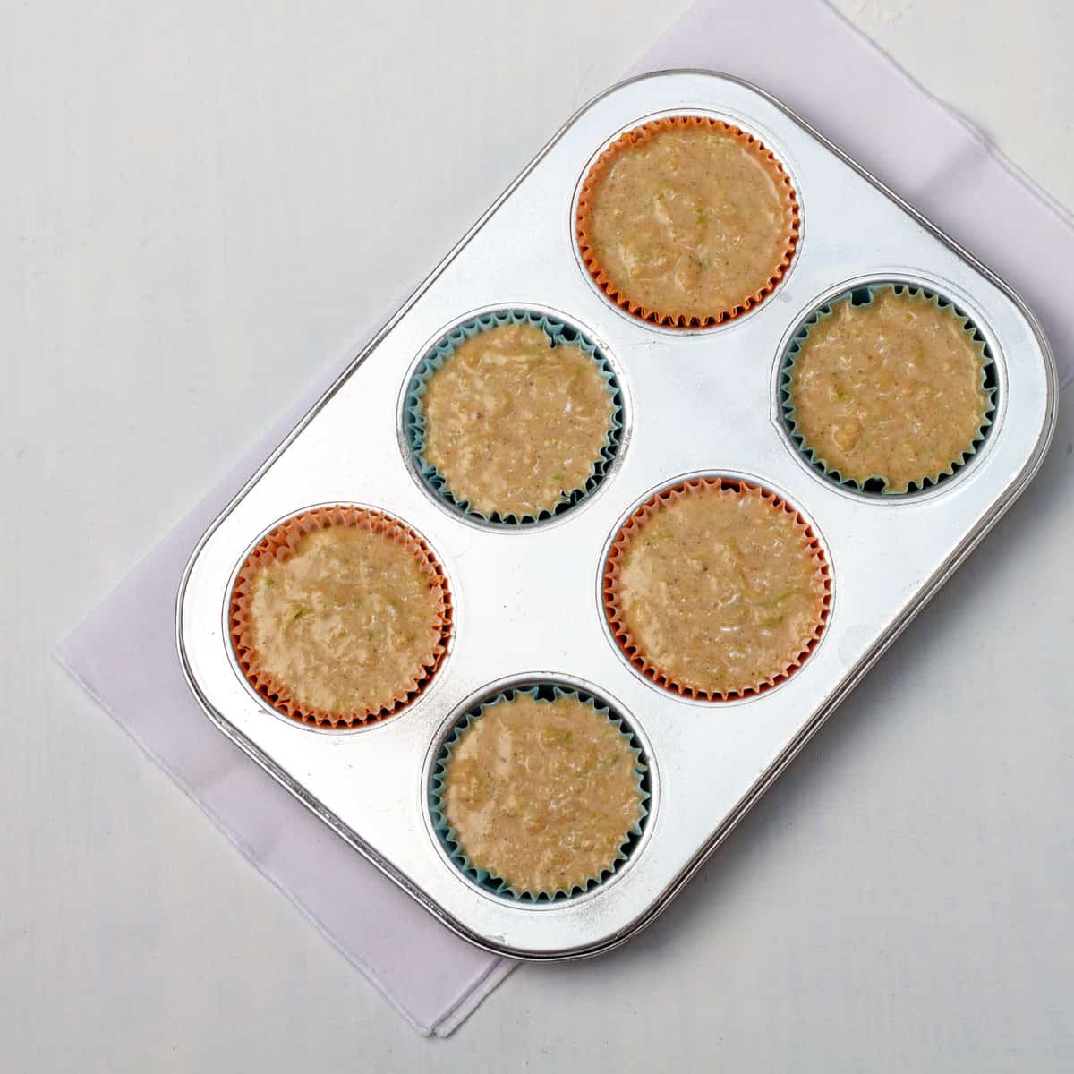 All muffin batter ingredients poured into a muffin tin lined with paper liners. 