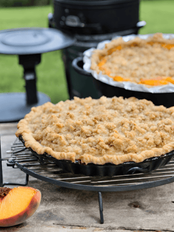 Maple Bourbon Peach Pie on cooling rack in front of Big Green Egg Grill